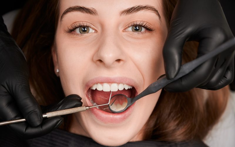 ręce dentysty badające zęby kobiety